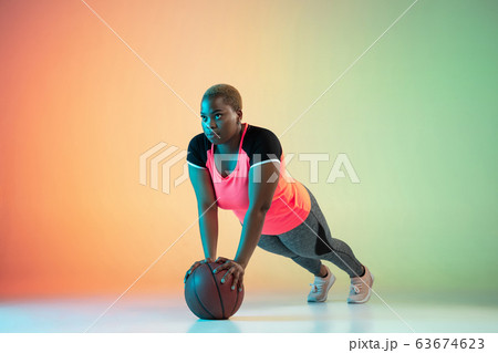 Young african-american plus size female model's training on gradient background 63674623