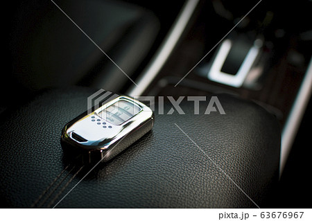 Keyless remote of luxury car on leather armrest in car. 63676967