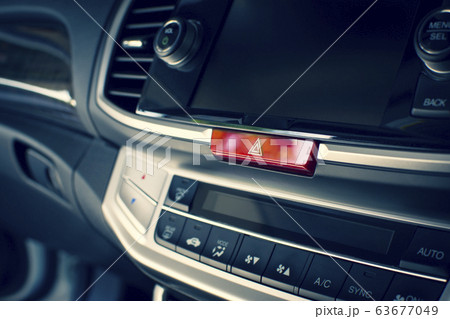 Car emergency light button on dashboard in a car. 63677049