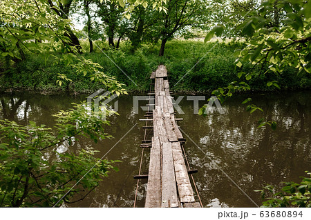 A small wooden bridge over a mild stream in a green park. A small wooden bridge over a mild stream in a green park. 63680894