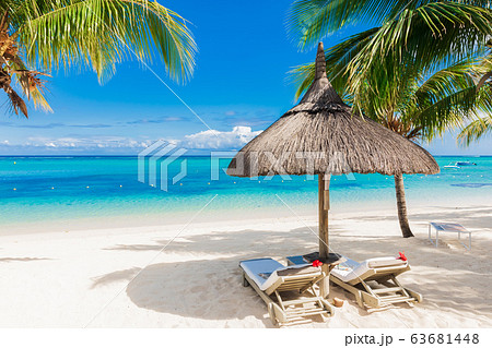 Chairs with umbrella at luxury beach with palms and blue ocean. Holiday banner 63681448