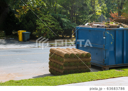 Stacks of sod rolls for new lawn and dumpster full 63683786