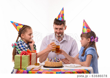 Kids and dad joyfully banging glasses of juice at Kids and dad joyfully banging glasses of juice at 63686078