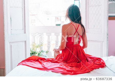 Young attractive woman in red dress on old balcony in apartment in Havana Young attractive woman in red dress on old balcony in apartment in Havana 63687336