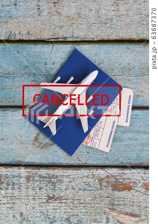 airplane, passport and tickets with a stamp in red text CANCELED on a blue wooden background 63687370