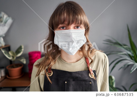 Portrait of Florist woman in a medical mask for protection from coronavirus. Pandemic concept, working during an epidemic. Small flower shop. Flowers delivery. Portrait of Florist woman in a medical mask for protection from coronavirus. Pandemic concept, working during an epidemic. Small flower shop. Flowers delivery. 63687535
