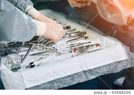 The surgeon's hands are holding an operating tool in the operating room. Close-up, beautiful light, modern medicine, Saving lives. The surgeon's hands are holding an operating tool in the operating room. Close-up, beautiful light, modern medicine, Saving lives. 63688209