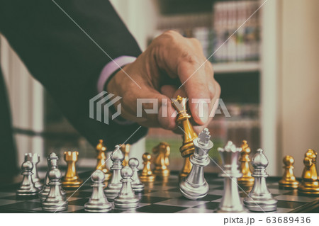 Chess game on chess board behind business man 63689436