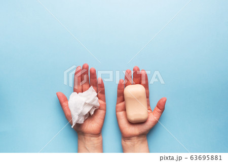 Natural soap and a wet cloth in the hands of women on a blue background. Concept of choice for hand cleanliness. Copy space. Natural soap and a wet cloth in the hands of women on a blue background. Concept of choice for hand cleanliness. Copy space. 63695881