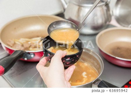 具だくさんのみそ汁を入れる女性の手元 63695942
