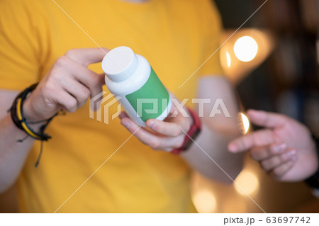 Close up picture of a man holding a jar with pills Close up picture of a man holding a jar with pills 63697742