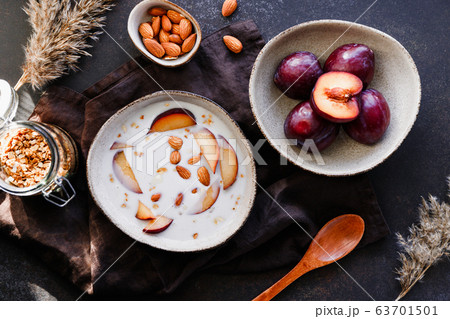 High angle view of morning porridge with almond and sliced plum. Healthy energy breakfast. 63701501