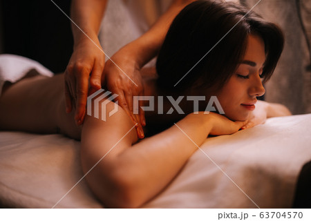 Young attractive woman gets professional shoulder massage in spa salon. 63704570