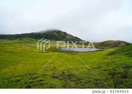 雲で隠れた山頂と草原と池が見える熊本草千里 63704914