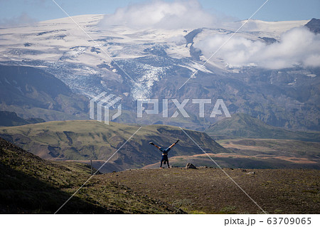 young guy standing on his hands with snowy mountain and glacier background on the way of Laugavegur trail, Iceland. Promoting activity and healthy lifestyle 63709065