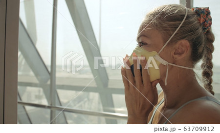 Woman caucasian at airport with wearing protective medical mask on head against the background of the plane. Coronavirus sars-cov-2 covid-19. Woman caucasian at airport with wearing protective medical mask on head against the background of the plane. Coronavirus sars-cov-2 covid-19. 63709912