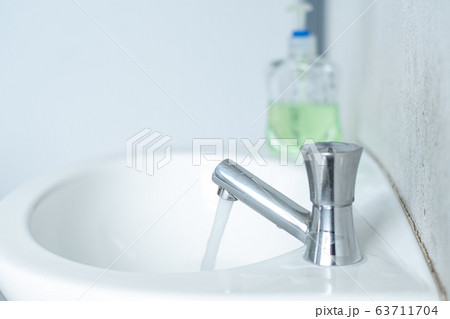 The tap that opens the water in the white bathroom with a hand sanitizer to clean the hands. 63711704