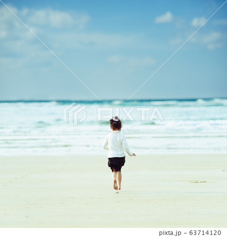 海に向かって走る女の子の後ろ姿の写真素材