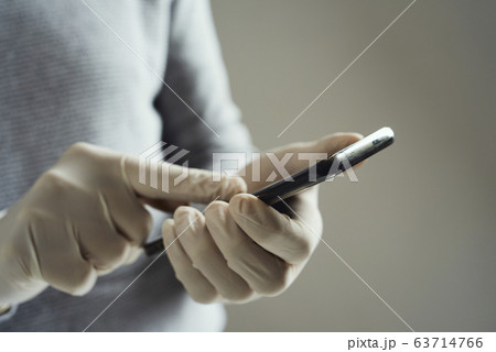 man wearing latex gloves using his smartphone man wearing latex gloves using his smartphone 63714766