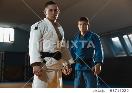 Two young judo fighters in kimono posing comfident in the gym, strong and healthy Two young judo fighters in kimono posing comfident in the gym, strong and healthy 63715029