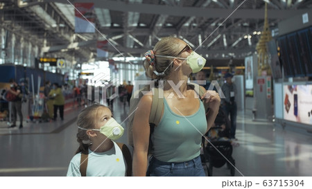 Woman and child baby tourist caucasian at airport with wearing protective medical mask. Family in quarantine isolation. Coronavirus covid-19. Woman and child baby tourist caucasian at airport with wearing protective medical mask. Family in quarantine isolation. Coronavirus covid-19. 63715304