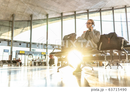 Woman stucked at airport terminal over flight cancellation,calling family, sitting in almost empty airport terminal due to coronavirus pandemic, Covid 19, outbreak travel restrictions 63715490
