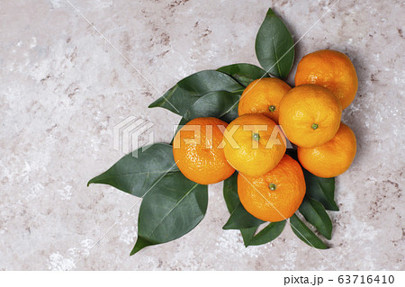 Tangerines (oranges, clementines, citrus fruits) with green leaves on concrete background with copy space 63716410