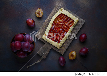 Fresh plum galette pie with raw plums on dark background 63716505