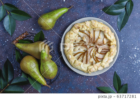 Homemade pear galette pie with almond leaves and fresh ripe green pears 63717281