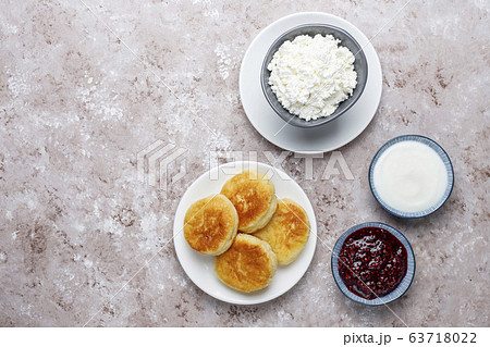 Cottage cheese pancakes.Russian syrniki or sirniki, cottage cheese fritters or pancakes with a bowl of fresh homemade cottage cheese on light background Cottage cheese pancakes.Russian syrniki or sirniki, cottage cheese fritters or pancakes with a bowl of fresh homemade cottage cheese on light background 63718022