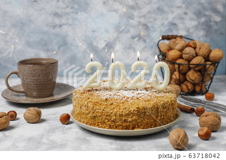 Carrot cake with 2020 candles and a cup of tea on grey concrete background Carrot cake with 2020 candles and a cup of tea on grey concrete background 63718042