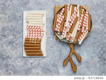 Plate with tasty wafer roll sticks on concrete background, top view. Crispy food Plate with tasty wafer roll sticks on concrete background, top view. Crispy food 63718046