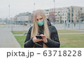 Young female wearing medical mask reading outbreaking news about coronavirus disease on the street 63718228