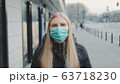 Young blonde woman wearing a protective medical mask on the street 63718230