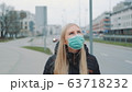 Concerned woman in medical coronavirus mask walking on the street 63718232