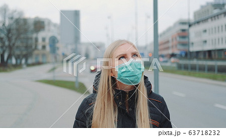 Concerned woman in medical coronavirus mask walking on the street Concerned woman in medical coronavirus mask walking on the street 63718232
