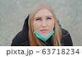 Crane shot of blonde woman looking into the sky and putting on medical mask 63718234