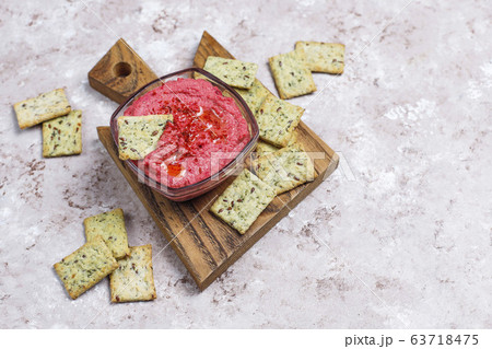 Beetroot hummus on cutting board with salty cookies on light background Beetroot hummus on cutting board with salty cookies on light background 63718475