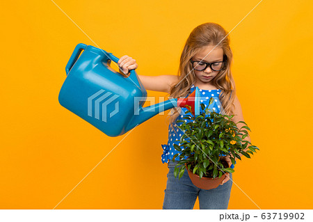 girl watering a potted houseplant on a yellow background with copy space girl watering a potted houseplant on a yellow background with copy space 63719902