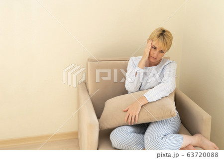 Woman at home sitting in armchair, feeling sick, 63720088