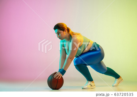 Young caucasian plus size female model's training on gradient purple green background Young caucasian plus size female model's training on gradient purple green background 63720535