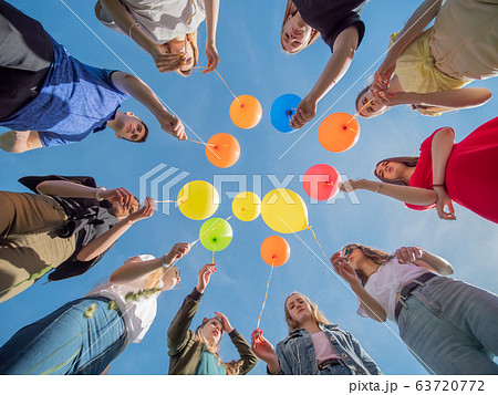Friends are holding colorful balloons in their hands. 63720772