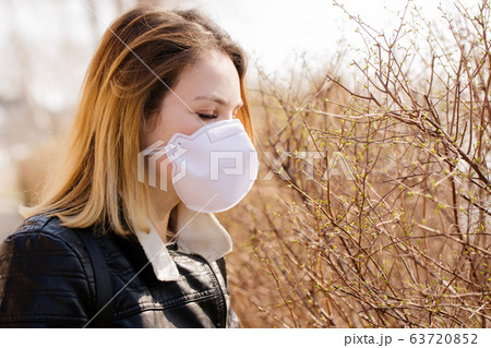 Woman trying to smell open leaves in a protective Woman trying to smell open leaves in a protective 63720852