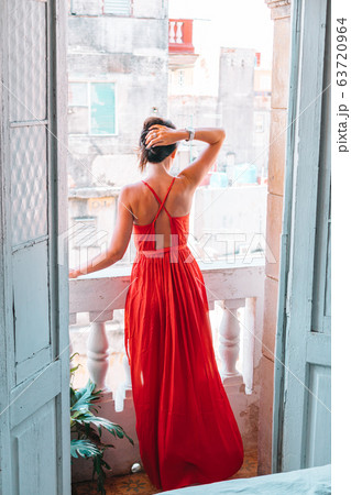 Young attractive woman in red dress on old balcony in apartment in Havana Young attractive woman in red dress on old balcony in apartment in Havana 63720964