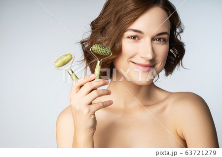 Portrait of cute female that demonstrating jade rollers Portrait of cute female that demonstrating jade rollers 63721279