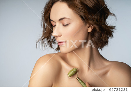 Relaxed young female person using jade roller Relaxed young female person using jade roller 63721281