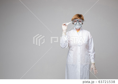 Physician in mask is holding thermometer in studio Physician in mask is holding thermometer in studio 63721538