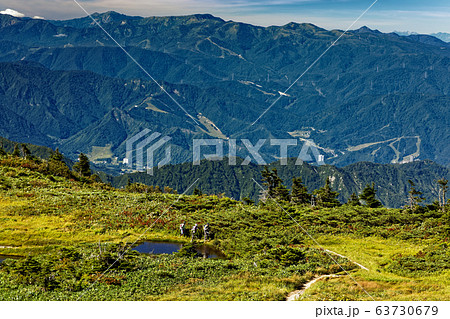 初秋の巻機山の湿原を行くとハイカーと苗場山方面の山並み 初秋の巻機山の湿原を行くとハイカーと苗場山方面の山並み 63730679