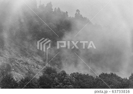 High mountain with green slopes hidden in clouds and fog 63733816