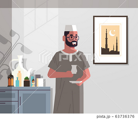 arabic man in traditional clothes drinking coffee celebrating ramadan kareem holy month modern living room interior flat vertical portrait 63736376